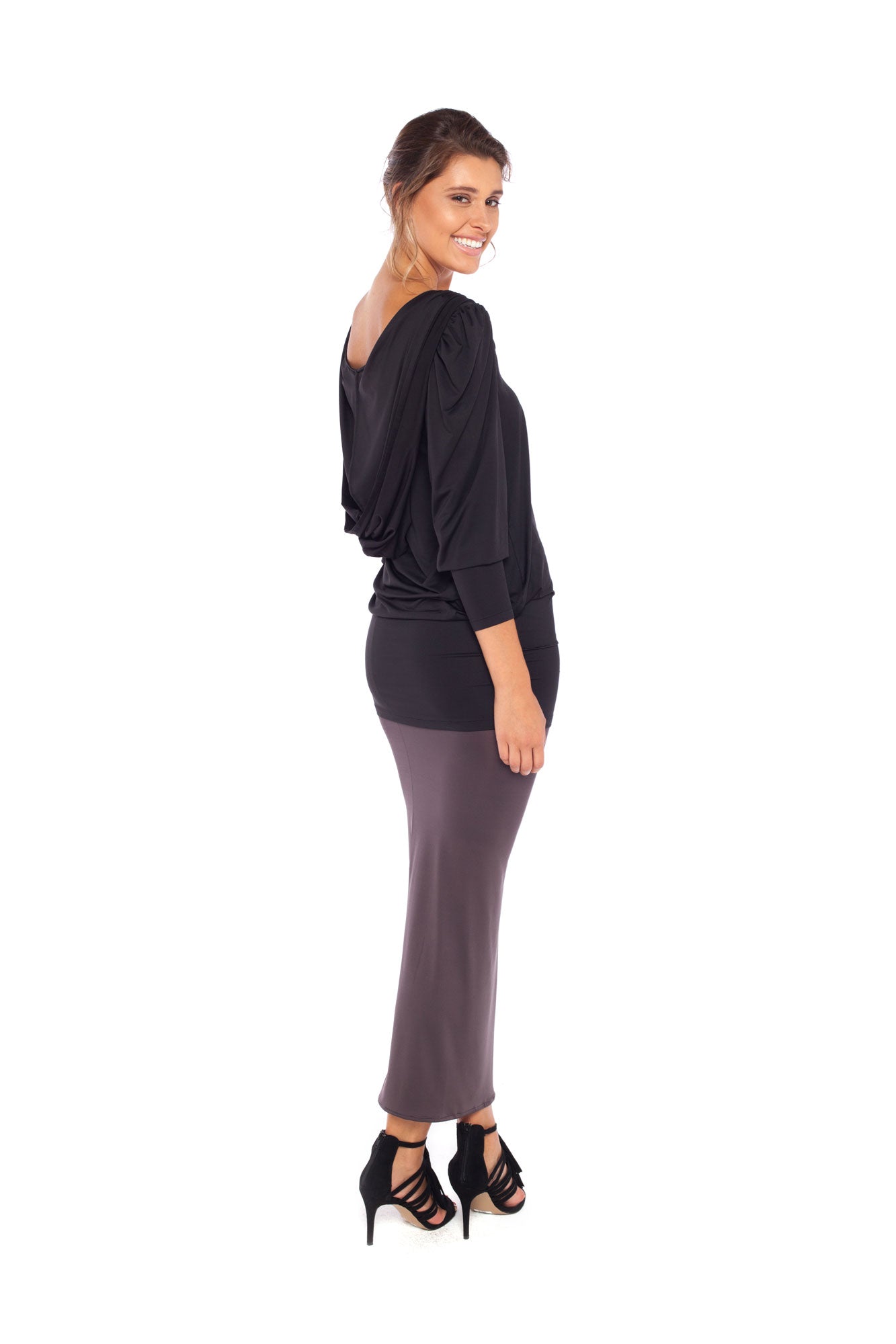 Side view of a size 10 woman wearing a long sleeve hoodie top in black slinky jersey. The hoodie sweatshirt is worn with a slinky jersey tube skirt in khaki grey worn as a maxi skirt and styled for evening as a going out dress. Both hoodie top and tube skirt are by Australian fashion brand, Urban Silk who specialise in leisurewear clothing women can wear for work, travel and casual wear.