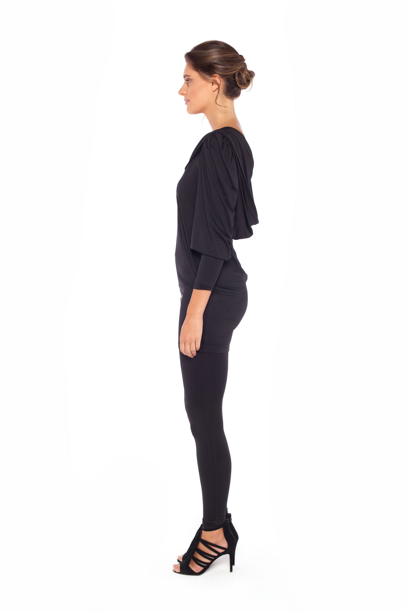 Side view of a woman wearing a long sleeve hoodie top in black slinky jersey. The hoodie sweatshirt is worn with black legging pants. Both hoodie top and legging pants are by Australian fashion brand, Urban Silk who specialise in leisurewear clothing women can wear for work, travel and casual wear. Shop women's leisurewear  online in petite to plus sizes.