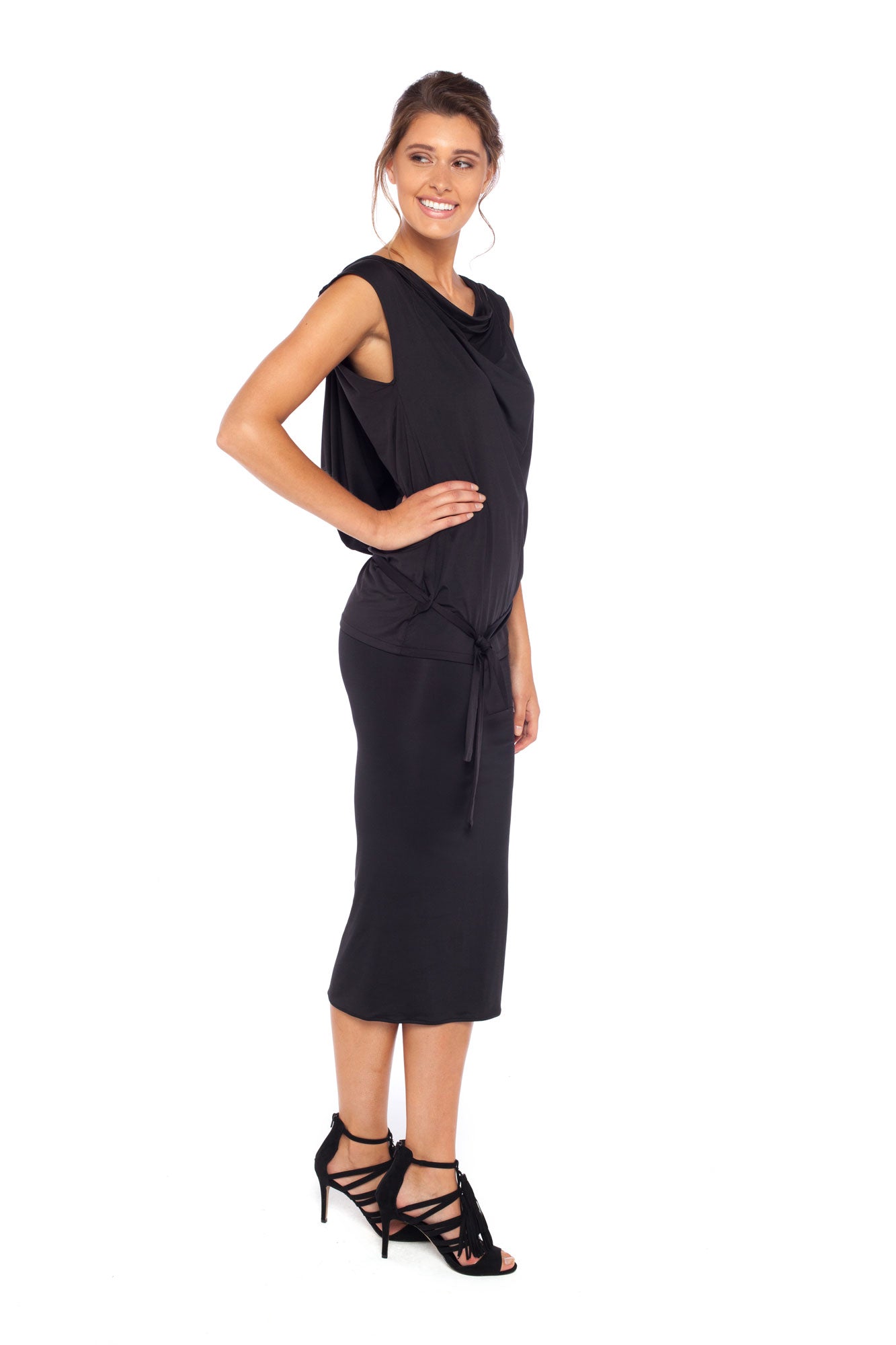 Side view of a woman wearing a black hooded top in slinky jersey worn with black tube skirt in stretch jersey and styled with heels to show leisurewear fashion that can be worn for work, casual wear and low-key evening looks. Shop leisurewear designed in Australia for petite to curvy women at Urban Silk