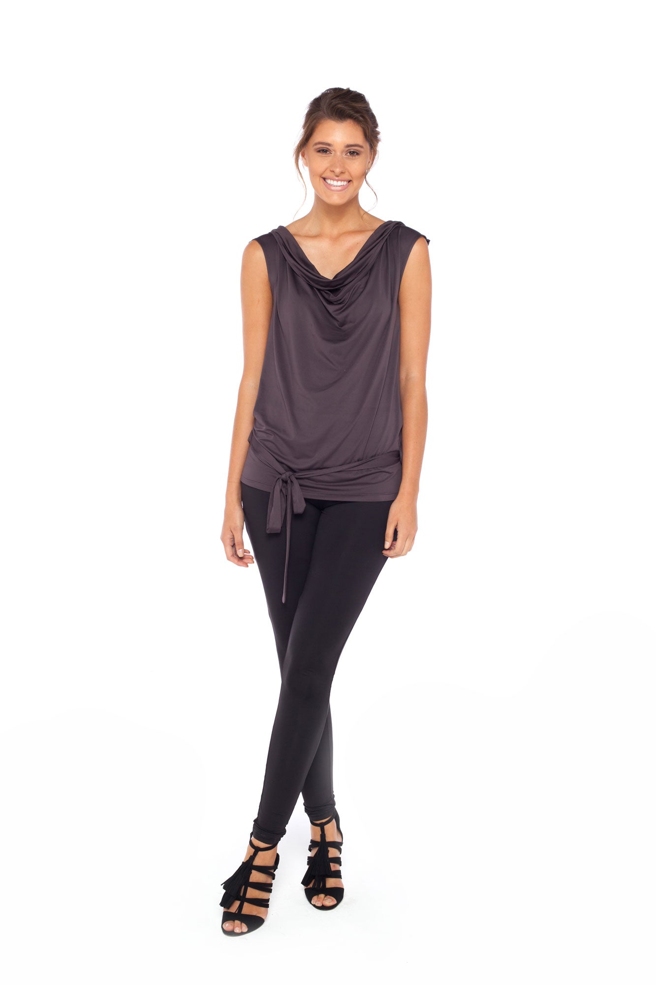 A woman wears Urban Silk leisurewear's Sleeveless Hooded Top in khaki grey. Featuring an oversized hood with elegant drape the slinky jersey fabric is full of stretch comfort for petite to plus size, curvy women. Worn with a slinky black legging pant, this is casual wear comfort elevated for luxe weekend wardrobes. Shop leisurewear in Australia at online women's leisure brand, Urban Silk clothing.